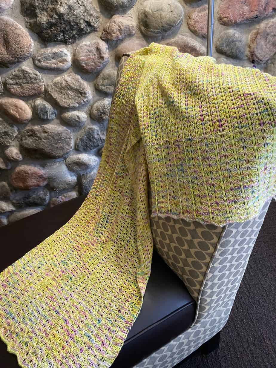 Goiong Postal Wrap (a knitted shawl) draped on a chair