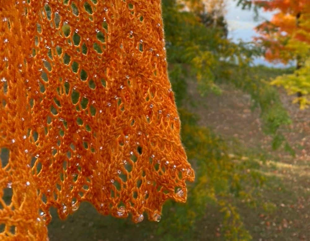 Barton Cottage Shawl swaying in front of fall trees, designed by Magda Stryk Therrien (Magda Makes)